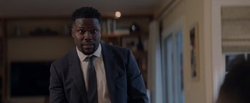 Movie still from “Me Time” (2022), directed by John Hamburg – A man wearing a suit and tie standing in a room; Close Up shot, Over the shoulder angle