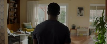 Movie still from “Me Time” (2022), directed by John Hamburg – A man standing in front of a living room window; Medium shot, Over the shoulder angle