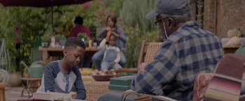 Movie still from “Me Time” (2022), directed by John Hamburg – An older man and a young boy sitting on a lawn chair; Medium shot, Over the shoulder angle
