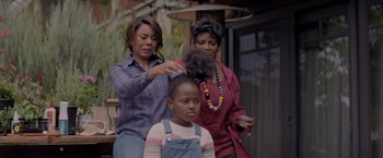 Movie still from “Me Time” (2022), directed by John Hamburg – Three women blow drying a child's hair outside; Medium shot, Over the shoulder angle