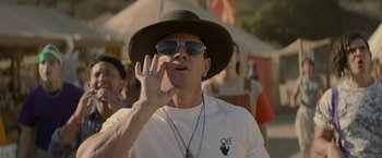 Movie still from “Me Time” (2022), directed by John Hamburg – A man wearing a hat and sunglasses while talking on a cell phone; Close Up shot, Over the shoulder angle