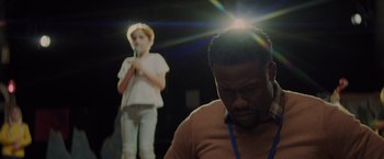 Movie still from “Me Time” (2022), directed by John Hamburg – A man and a girl are standing in front of a microphone; Close Up shot, Over the shoulder angle