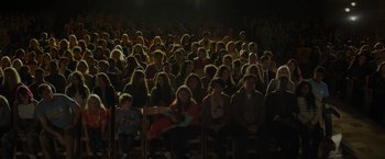 Movie still from “Me Time” (2022), directed by John Hamburg – A group of people sitting in rows in front of an audience; Extreme Wide shot, High angle