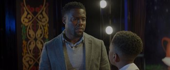 Movie still from “Me Time” (2022), directed by John Hamburg – A man wearing a suit and tie standing next to another man wearing a jacket; Close Up shot, Over the shoulder angle