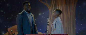 Movie still from “Me Time” (2022), directed by John Hamburg – Two men standing next to each other in front of microphones; Medium shot, Over the shoulder angle