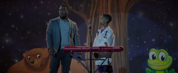 Movie still from “Me Time” (2022), directed by John Hamburg – Two young men standing in front of a microphone; Medium shot, Over the shoulder angle