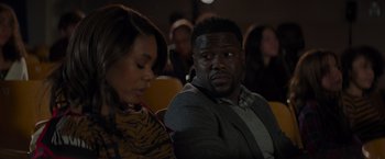 Movie still from “Me Time” (2022), directed by John Hamburg – A man and a woman sitting in front of an audience; Medium shot, Over the shoulder angle