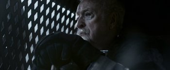 Movie still from “Medieval” (2022), directed by Petr Jákl – An older man looking out a window at night; Close Up shot, Over the shoulder angle