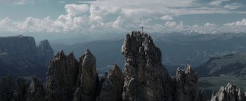 Movie still from “Medieval” (2022), directed by Petr Jákl – A cross on top of a mountain with a sky background; Extreme Wide shot, Low angle