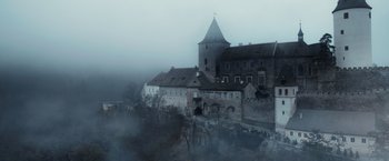 Movie still from “Medieval” (2022), directed by Petr Jákl – A castle with a tower on top of a hill in the middle of the night; Extreme Wide shot, High angle