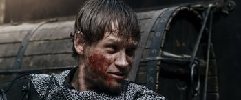 Movie still from “Medieval” (2022), directed by Petr Jákl – A person with blood on his face; Close Up shot, Over the shoulder angle
