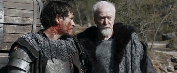 Movie still from “Medieval” (2022), directed by Petr Jákl – Two men in medieval garb standing next to each other; Medium shot, Over the shoulder angle