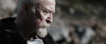 Movie still from “Medieval” (2022), directed by Petr Jákl – An old man with a beard and a mustache looking to his left; Close Up shot, Low angle