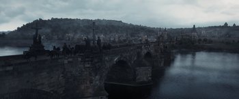 Movie still from “Medieval” (2022), directed by Petr Jákl – A view of a bridge and a city in the background; Extreme Wide shot, High angle