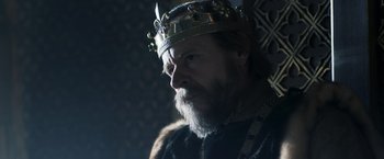 Movie still from “Medieval” (2022), directed by Petr Jákl – A man with a beard wearing a crown; Close Up shot, Over the shoulder angle