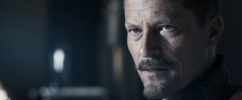 Movie still from “Medieval” (2022), directed by Petr Jákl – A person with a beard and mustache; Close Up shot, Over the shoulder angle