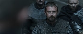 Movie still from “Medieval” (2022), directed by Petr Jákl – A man with a beard in a chain mail outfit; Close Up shot, Low angle