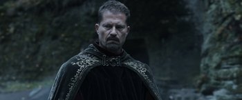 Movie still from “Medieval” (2022), directed by Petr Jákl – A person wearing a cape; Close Up shot, Low angle