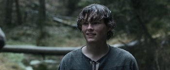Movie still from “Medieval” (2022), directed by Petr Jákl – A young man in a black shirt is looking at the camera; Close Up shot, Low angle