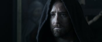 Movie still from “Medieval” (2022), directed by Petr Jákl – A man with a beard wearing a hooded sweatshirt; Close Up shot, Over the shoulder angle