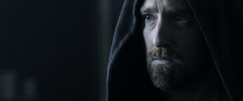 Movie still from “Medieval” (2022), directed by Petr Jákl – A man with a beard wearing a hooded sweatshirt; Close Up shot, Over the shoulder angle
