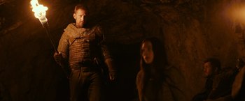 Movie still from “Medieval” (2022), directed by Petr Jákl – A man and a woman standing next to each other in a cave; Medium shot, Over the shoulder angle