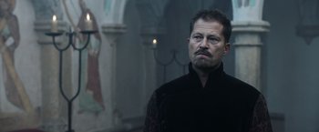 Movie still from “Medieval” (2022), directed by Petr Jákl – A person wearing a black shirt; Close Up shot, Low angle