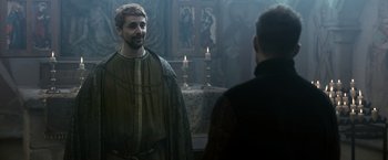 Movie still from “Medieval” (2022), directed by Petr Jákl – A man in a green robe standing next to a man in a black robe; Medium shot, Over the shoulder angle