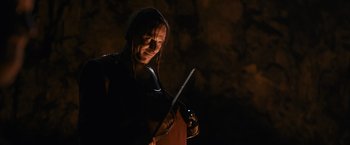 Movie still from “Medieval” (2022), directed by Petr Jákl – A man holding a sword in a dark room; Close Up shot, Low angle
