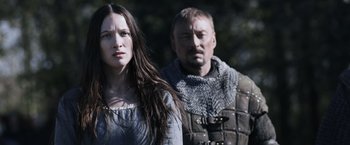 Movie still from “Medieval” (2022), directed by Petr Jákl – A man and a woman standing next to each other; Close Up shot, Low angle