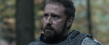 Movie still from “Medieval” (2022), directed by Petr Jákl – A person wearing a chainmail jacket; Close Up shot, Low angle