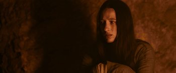 Movie still from “Medieval” (2022), directed by Petr Jákl – A woman with long dark hair sitting in a dark room; Close Up shot, Low angle