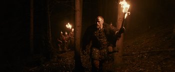 Movie still from “Medieval” (2022), directed by Petr Jákl – A group of people in the woods holding torches; Wide shot, Low angle