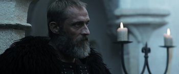 Movie still from “Medieval” (2022), directed by Petr Jákl – A man with a long beard is looking to his left; Close Up shot, Low angle