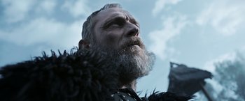 Movie still from “Medieval” (2022), directed by Petr Jákl – A man with a long beard looking up into the sky; Close Up shot, Low angle