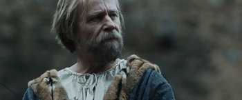 Movie still from “Medieval” (2022), directed by Petr Jákl – An old man with a beard and a long beard; Close Up shot, Over the shoulder angle