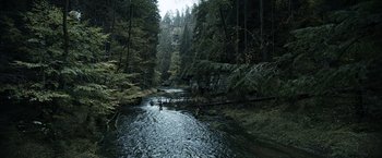 Movie still from “Medieval” (2022), directed by Petr Jákl – A couple of people in a river near a forest; Extreme Wide shot, High angle