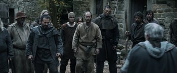 Movie still from “Medieval” (2022), directed by Petr Jákl – A group of men standing next to each other in the woods; Medium shot, Low angle