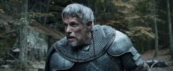 Movie still from “Medieval” (2022), directed by Petr Jákl – A person wearing a suit of armor; Close Up shot, Over the shoulder angle