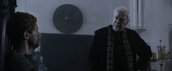 Movie still from “Medieval” (2022), directed by Petr Jákl – An older man standing in front of a mirror; Medium shot, Over the shoulder angle