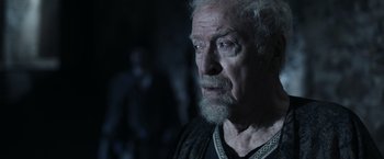 Movie still from “Medieval” (2022), directed by Petr Jákl – An old man with a beard and a mustache looking to his left; Close Up shot, Over the shoulder angle