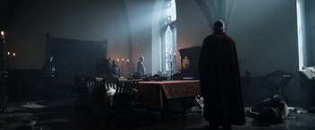 Movie still from “Medieval” (2022), directed by Petr Jákl – A group of people standing around a dining table; Wide shot, Low angle