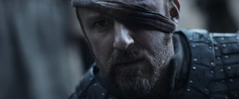 Movie still from “Medieval” (2022), directed by Petr Jákl – A person with a beard wearing a hat; Close Up shot, Over the shoulder angle