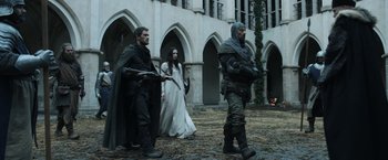 Movie still from “Medieval” (2022), directed by Petr Jákl – A group of people walking in front of a building; Wide shot, Low angle