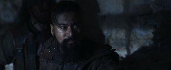 Movie still from “Medieval” (2022), directed by Petr Jákl – A man with a long beard wearing a leather jacket; Close Up shot, Over the shoulder angle