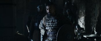 Movie still from “Medieval” (2022), directed by Petr Jákl – A man with a beard and a helmet on; Medium shot, Over the shoulder angle