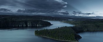 Movie still from “Medieval” (2022), directed by Petr Jákl – A body of water surrounded by a forest and mountains; Extreme Wide shot, High angle