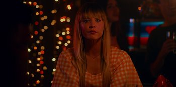 Movie still from “Meet Cute” (2022), directed by Alex Lehmann – A woman with long blonde hair sitting in front of lights; Close Up shot, Over the shoulder angle