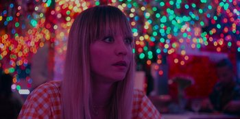 Movie still from “Meet Cute” (2022), directed by Alex Lehmann – A woman with blonde hair and a checkered shirt looking to her left; Close Up shot, Over the shoulder angle