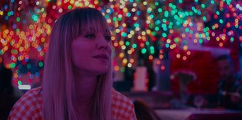 Movie still from “Meet Cute” (2022), directed by Alex Lehmann – A woman with blonde hair is sitting in front of lights; Close Up shot, Over the shoulder angle